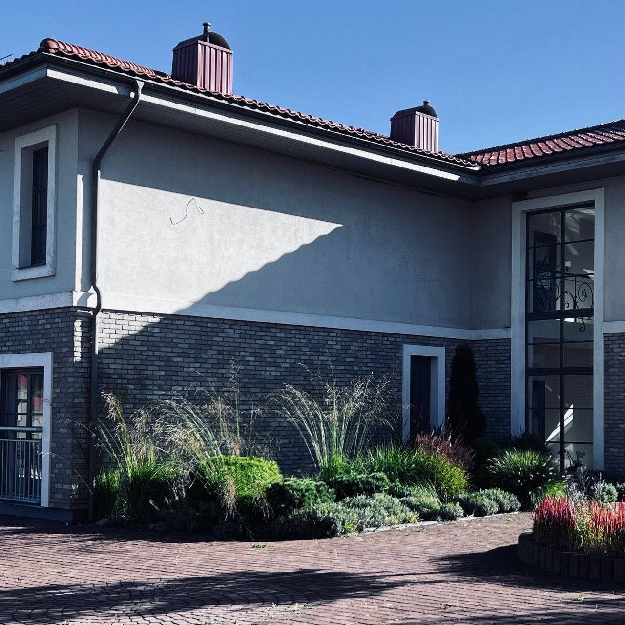 Šaltonės vilos kiemas su žydinčiomis smilgomis ir želdiniais